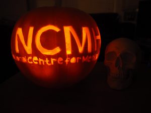 Photograph of a pumpkin with the 'NCMH' logo carved in the front