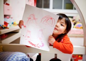 a little girl show her drawings on a piece of paper