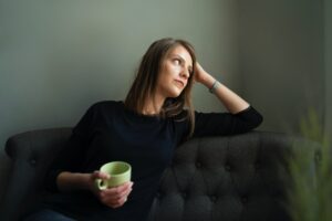 woman sat on sofa holding a mug in one hand