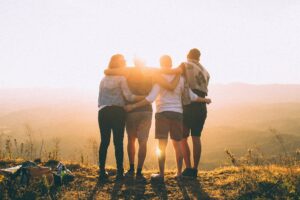group of four friends with their arms around each other looking out over a sunny view