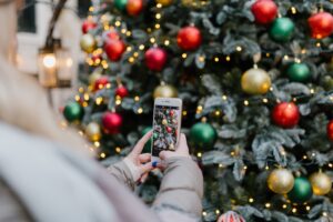 A person taking a photograph of a Christmas tree on their smartphone.