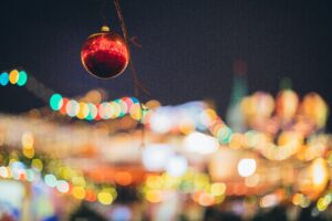 A Christmas bauble hangs in front of lights in the background