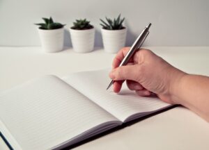 A person holding a pen about to write in a diary